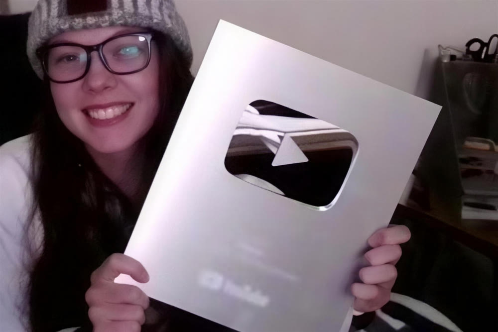 A creator holding a silver YouTube play button award on a video call
