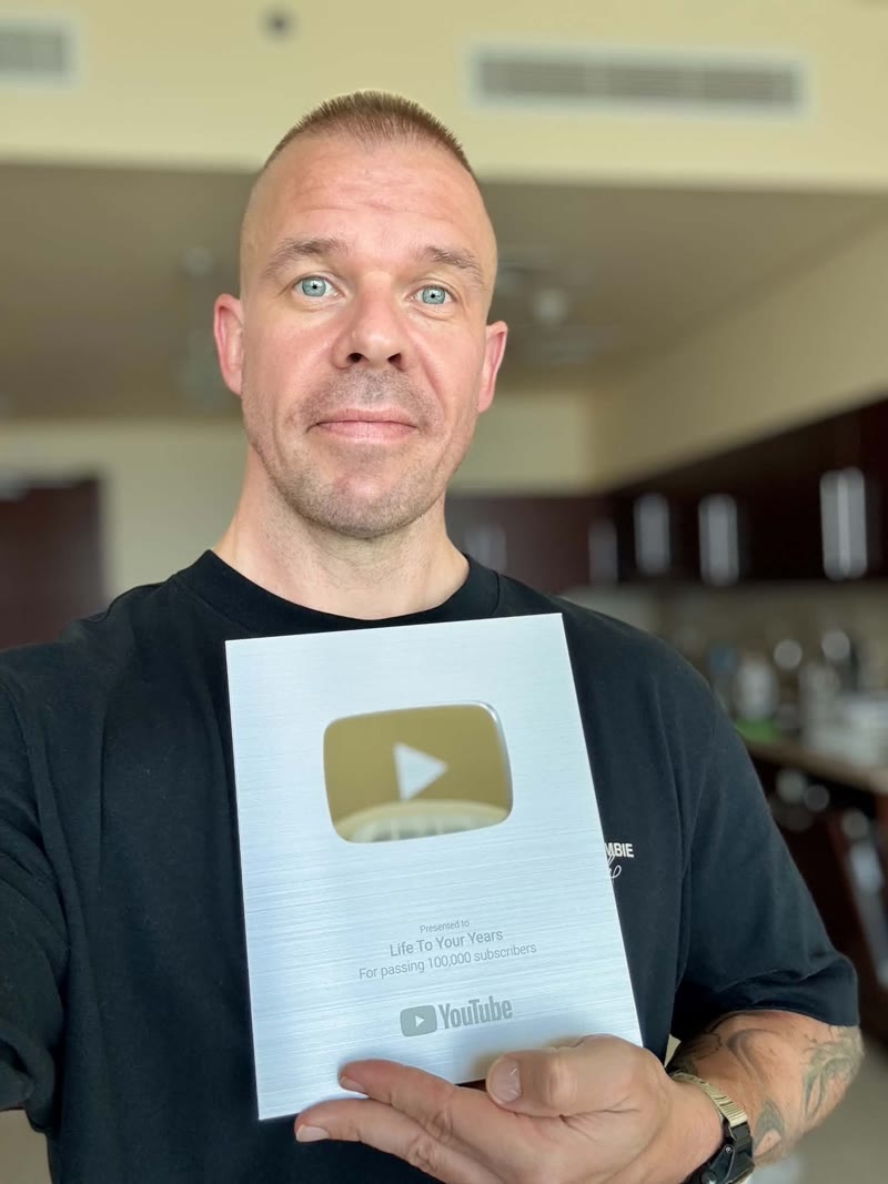 A creator holding a silver YouTube play button award in a kitchen