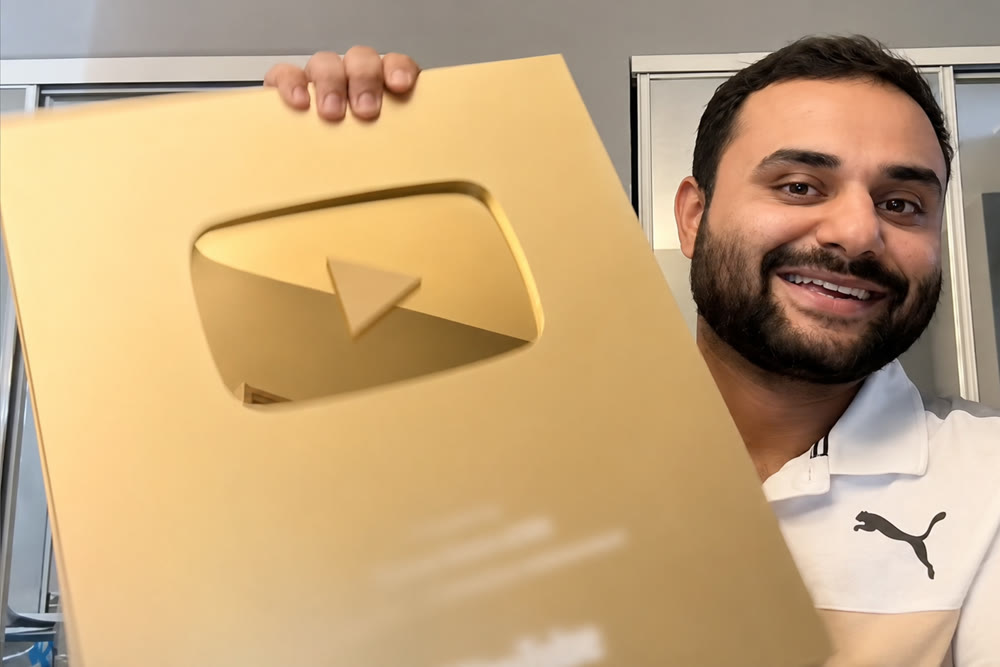 A creator holding up a large gold YouTube play button award, close up